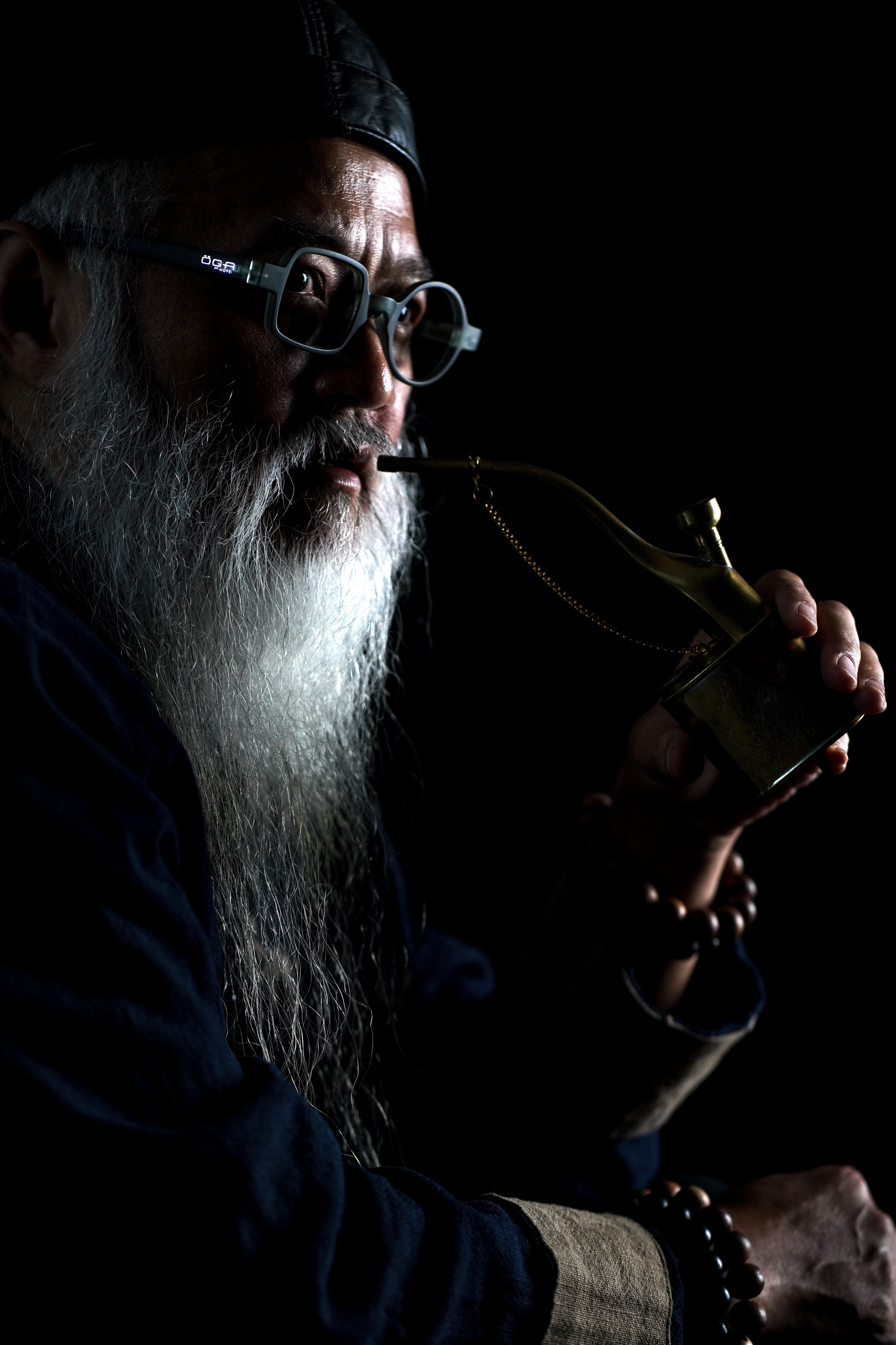 Dramatic low-key portrait of a bearded man with a pipe, shot in Bandung, Indonesia.