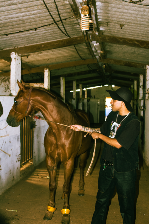 Free A man guides a horse through a rustic barn interior, showcasing equestrian culture. Stock Photo