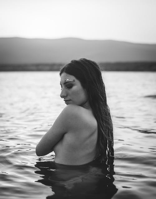 물에 토플리스 여자의 회색조 사진