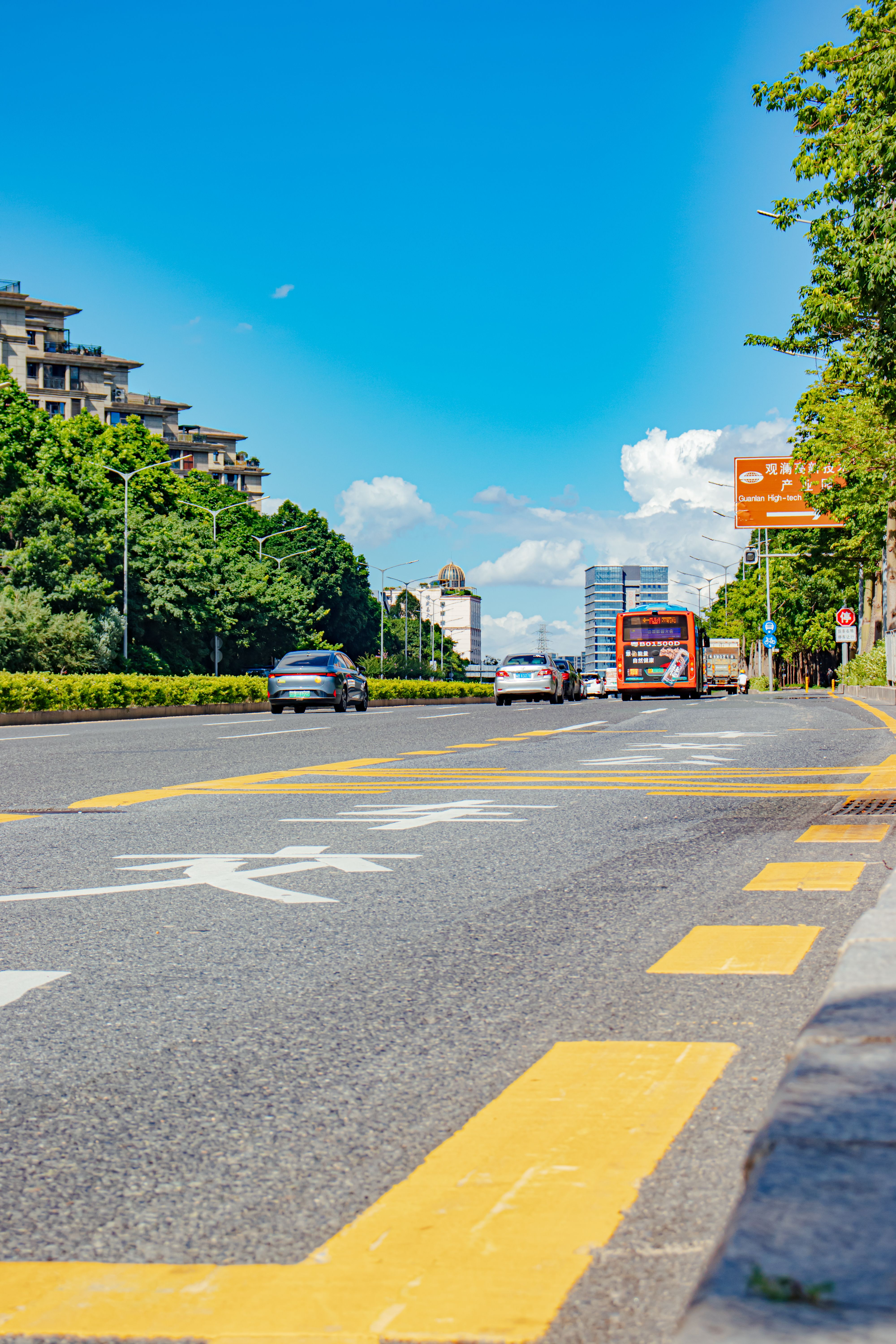 Vibrant city scene featuring a busy street with buses and cars under a clear blue sky.