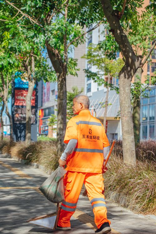 Free Elderly sanitation worker cleaning city street under bright sun. Stock Photo