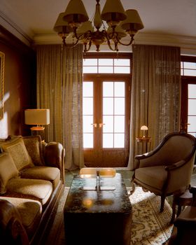 Elegant luxury living room filled with sunlight, featuring vintage furnishings and a classic chandelier.