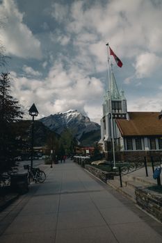 View of Banff Avenue with mountains and historic church in Banff, Canada.