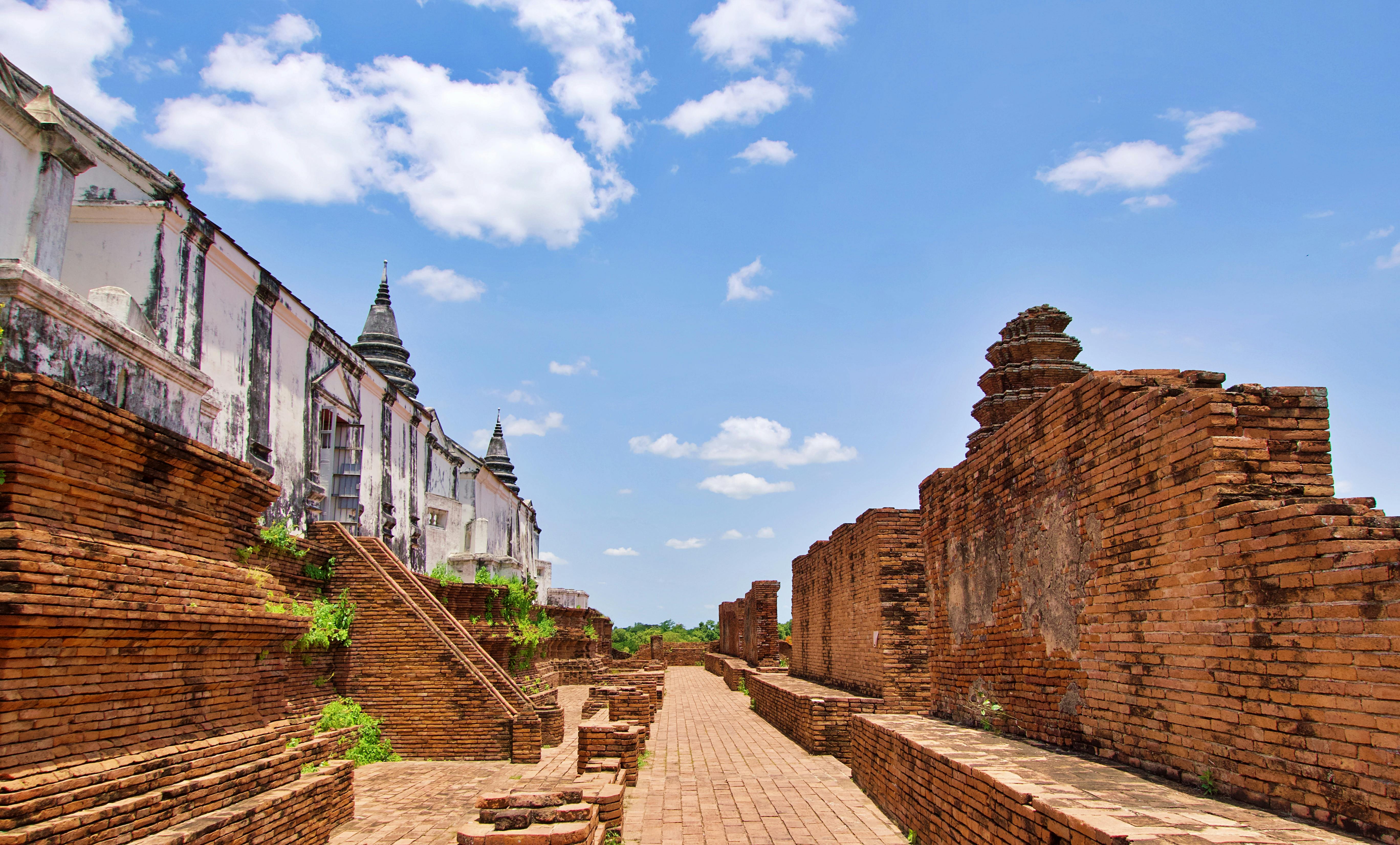 Explore the historic ruins of Ayutthaya, Thailand, showcasing ancient brick structures under a clear blue sky.