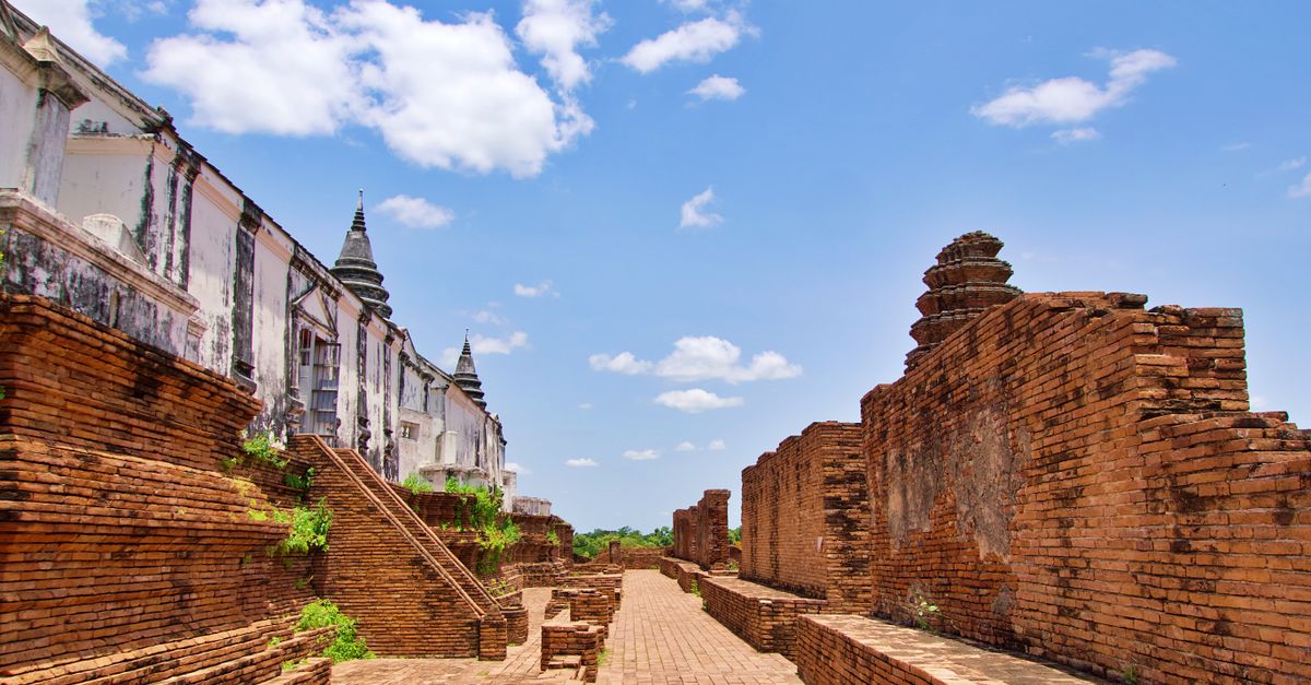 Explore the historic ruins of Ayutthaya, Thailand, showcasing ancient brick structures under a clear blue sky.