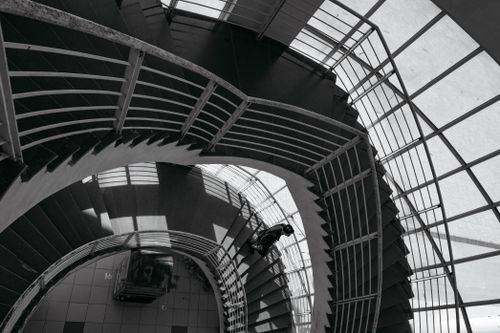 Free Artistic view of a spiral staircase in Hanoi with a person descending, captured in black and white. Stock Photo