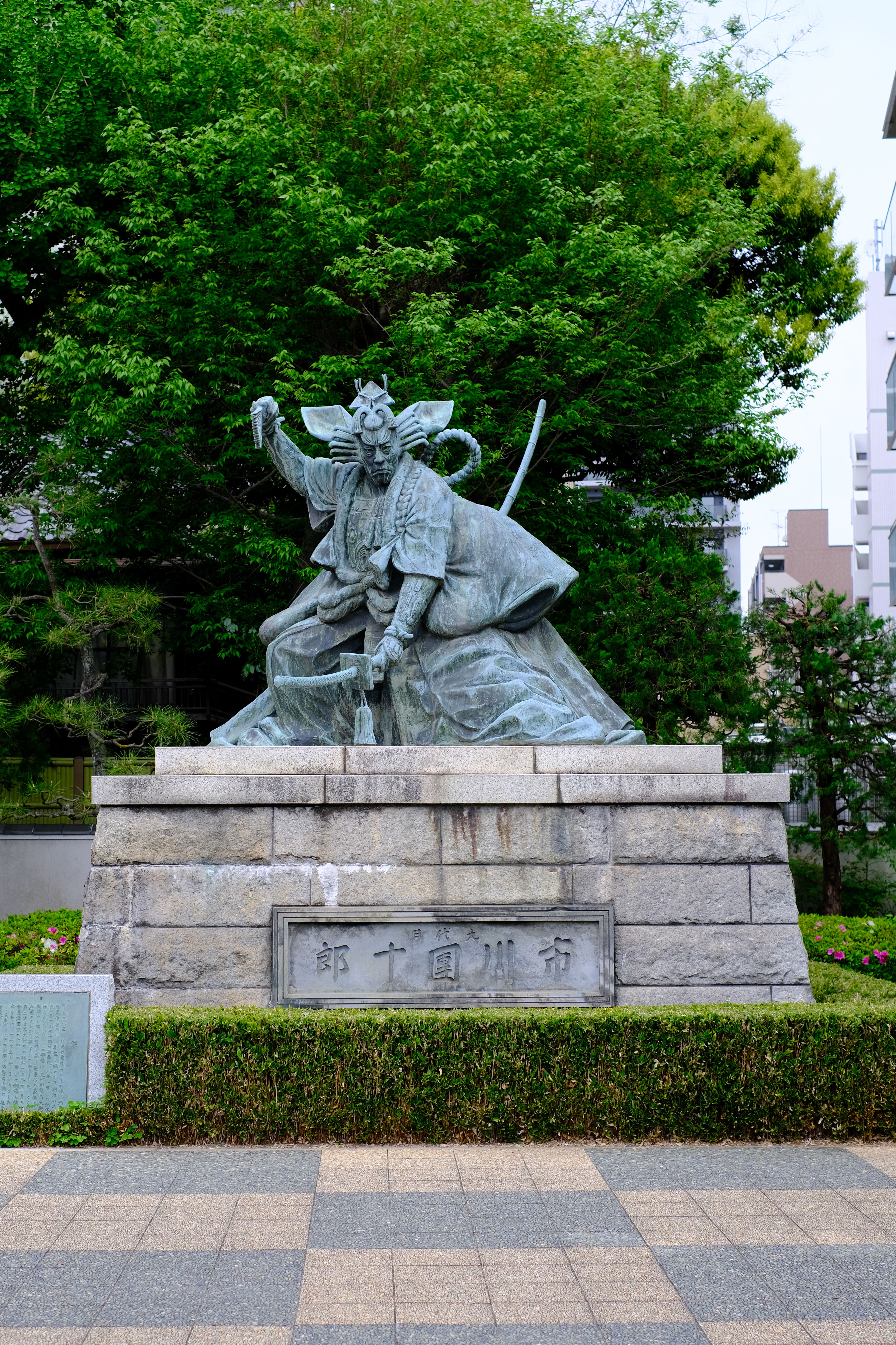 Bronze samurai statue in a scenic urban park setting, Japan.