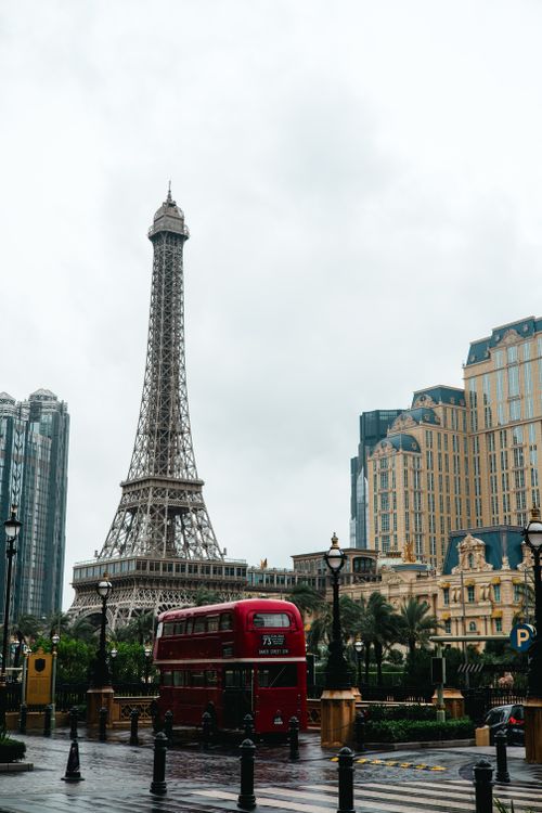 Free Eiffel Tower replica in Macau with a classic red bus on a cloudy day. Stock Photo