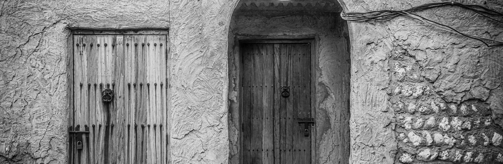 Black and white photo of traditional wooden doors in Dubai's historic Old Town.