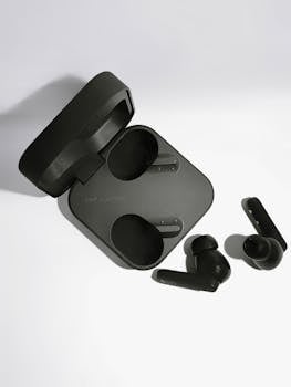 Black wireless earbuds and charging case on a white background with minimalist design.
