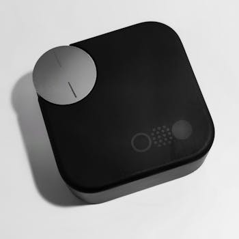 Minimalistic product shot of a black wireless audio device with sleek design on a white background.