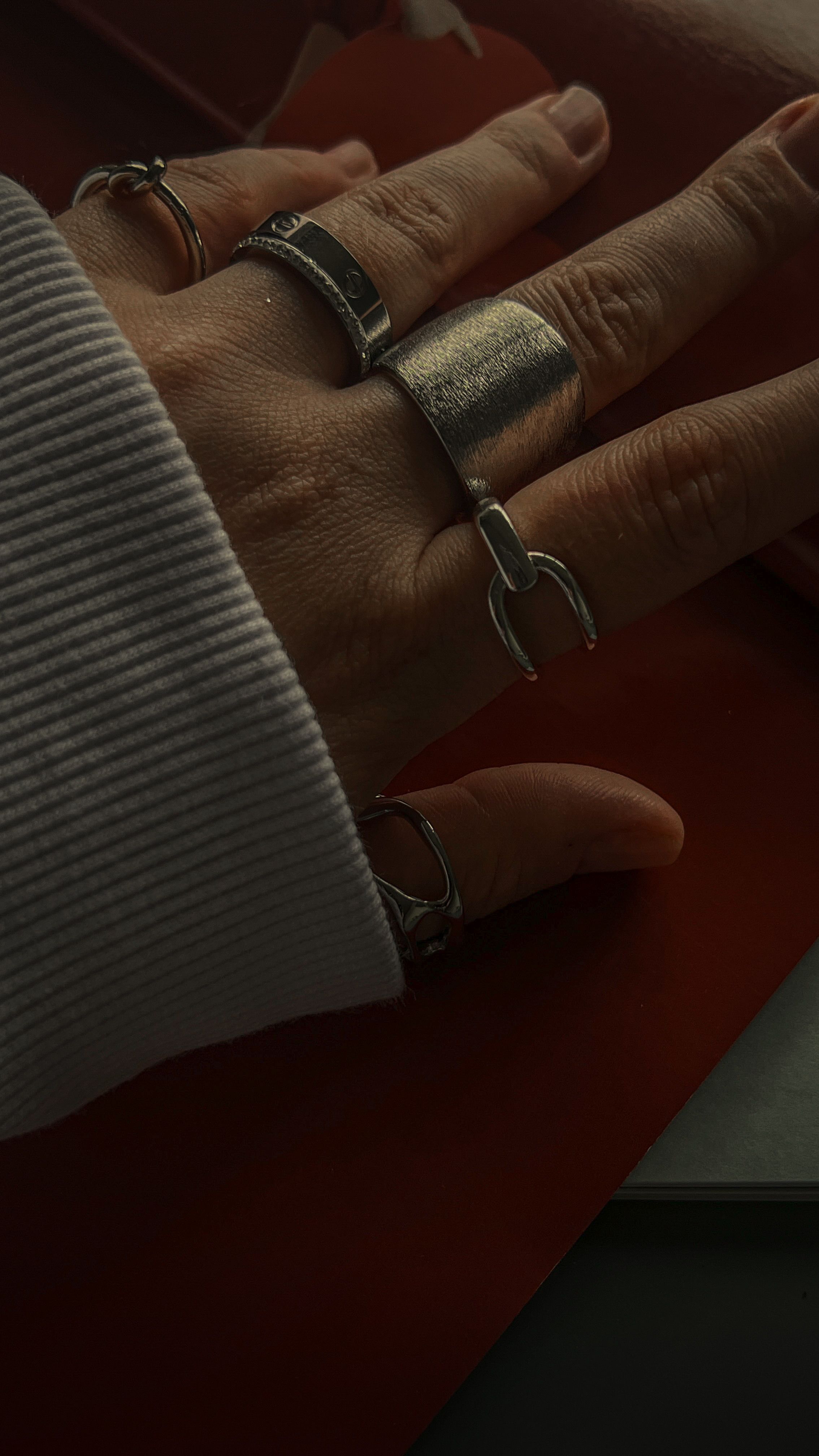 Close artístico de uma mão adornada com vários anéis de prata elegantes.