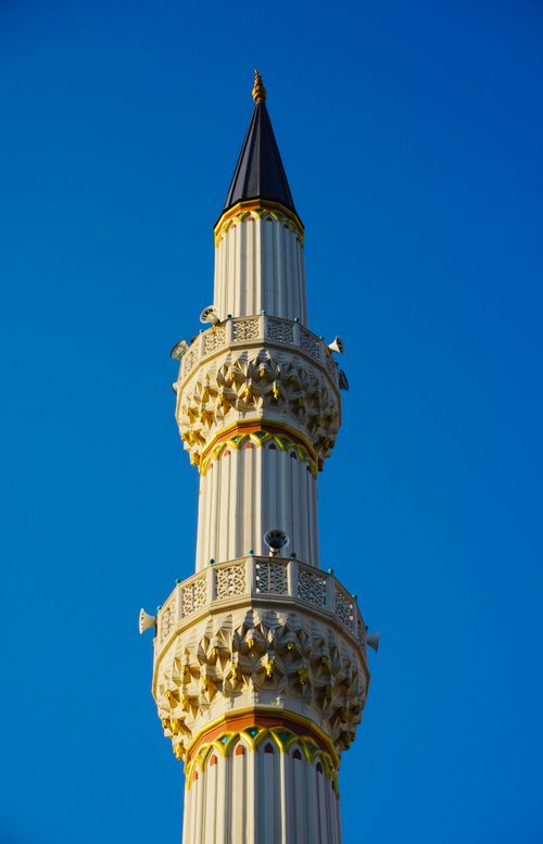 Free Elegant mosque minaret with intricate carvings standing against a bright blue sky, showcasing Islamic architecture. Stock Photo