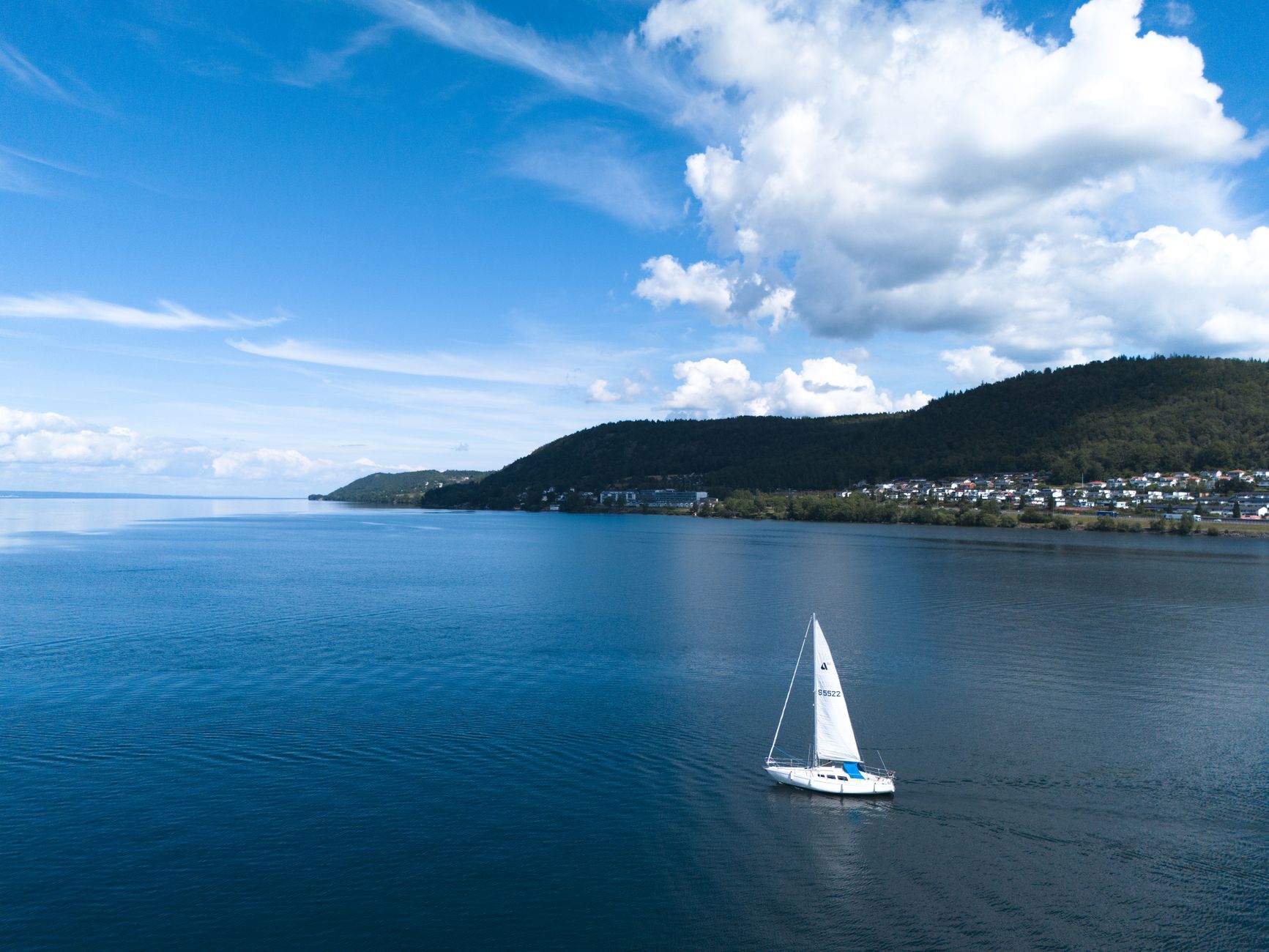 금 시세, 현명하게 알고 투자하는 2025년 최신 가이드 3 Aerial drone shot of a sailboat on calm blue waters near a lush green coastline in France.