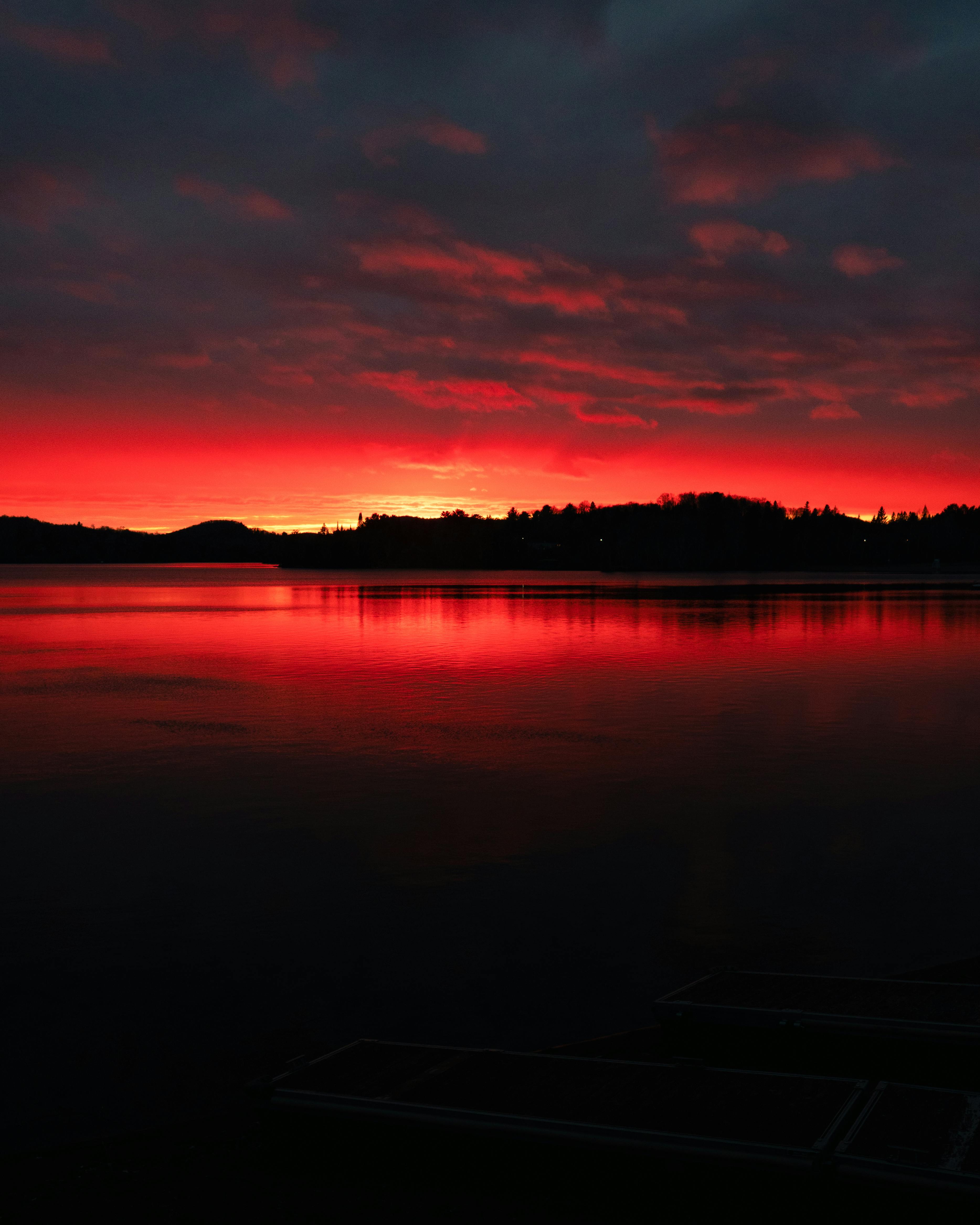 Stunning red and orange sunset over calm lake waters in Sainte-Agathe-des-Monts, Quebec.