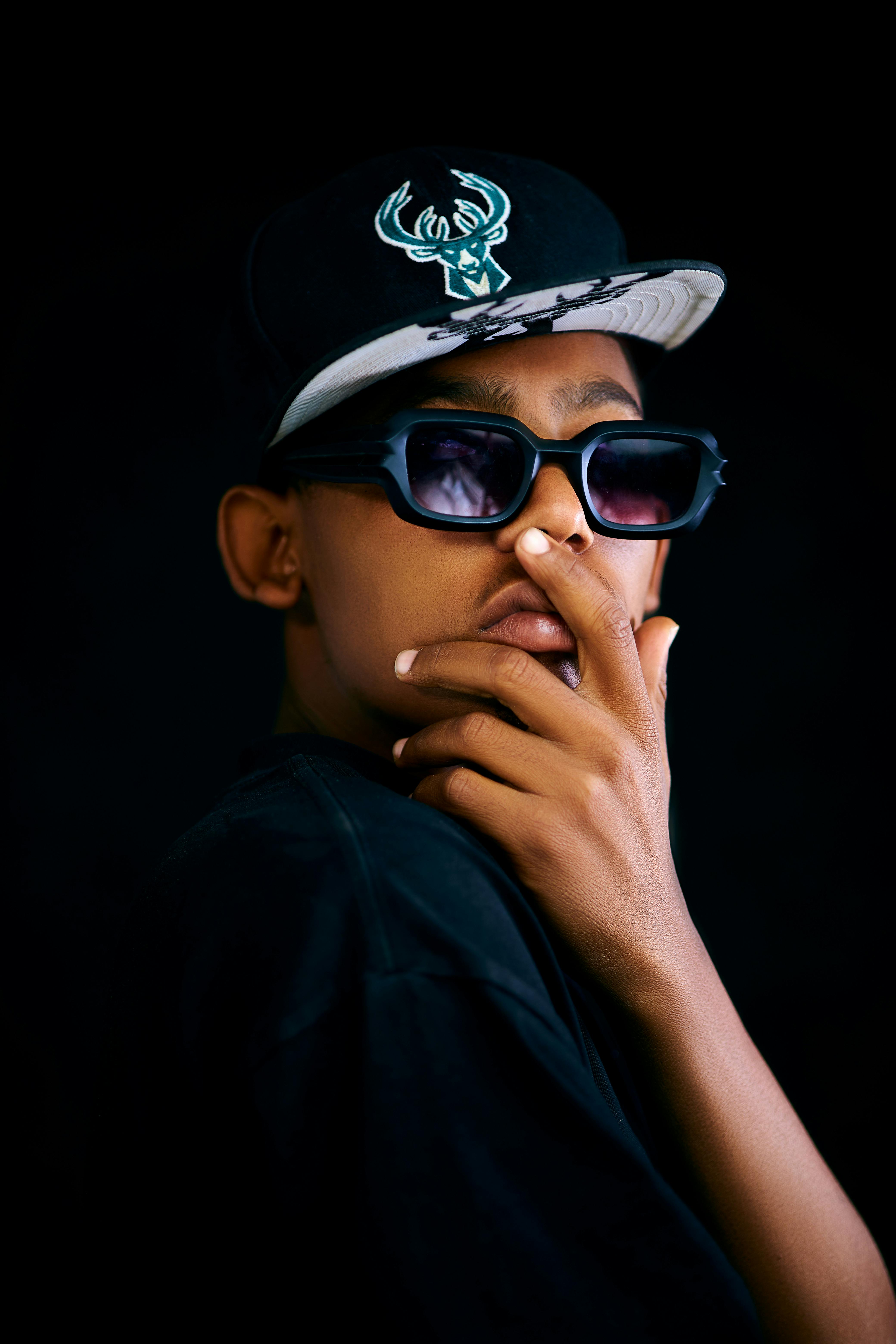 Fashionable young man with sunglasses and cap, showing style and attitude.