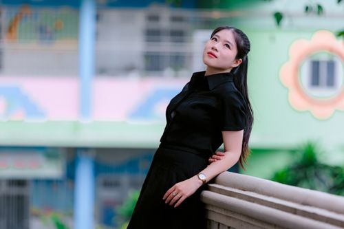Free A woman in black clothing leans contemplatively on a balcony with a pastel background. Stock Photo