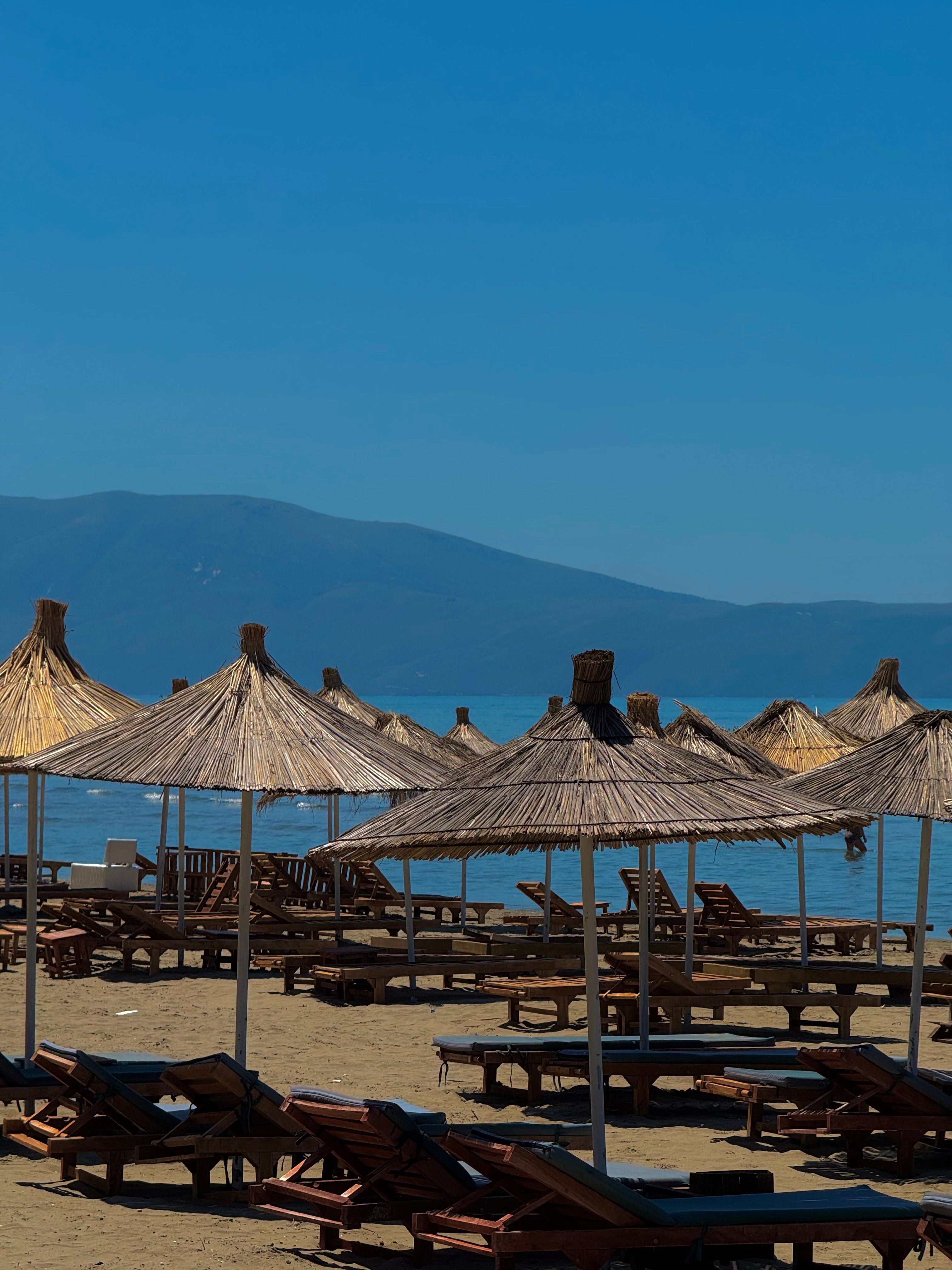 Relaxing beach scene in Vlore Albania with sunbeds and straw parasols overlooking the calm Adriatic sea