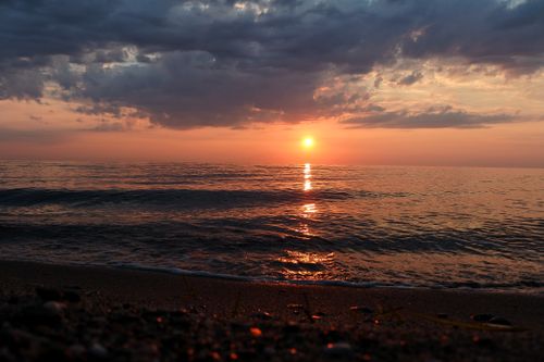 Free Peaceful sunset over the ocean with calm waves and vibrant reflections, creating a serene and warm atmosphere. Stock Photo