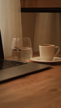 A warm, intimate setting with coffee, laptop, and water glass, perfect for focused work.