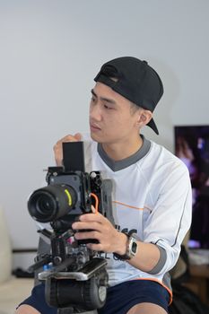 Young filmmaker adjusting professional camera setup indoors, focused and attentive.