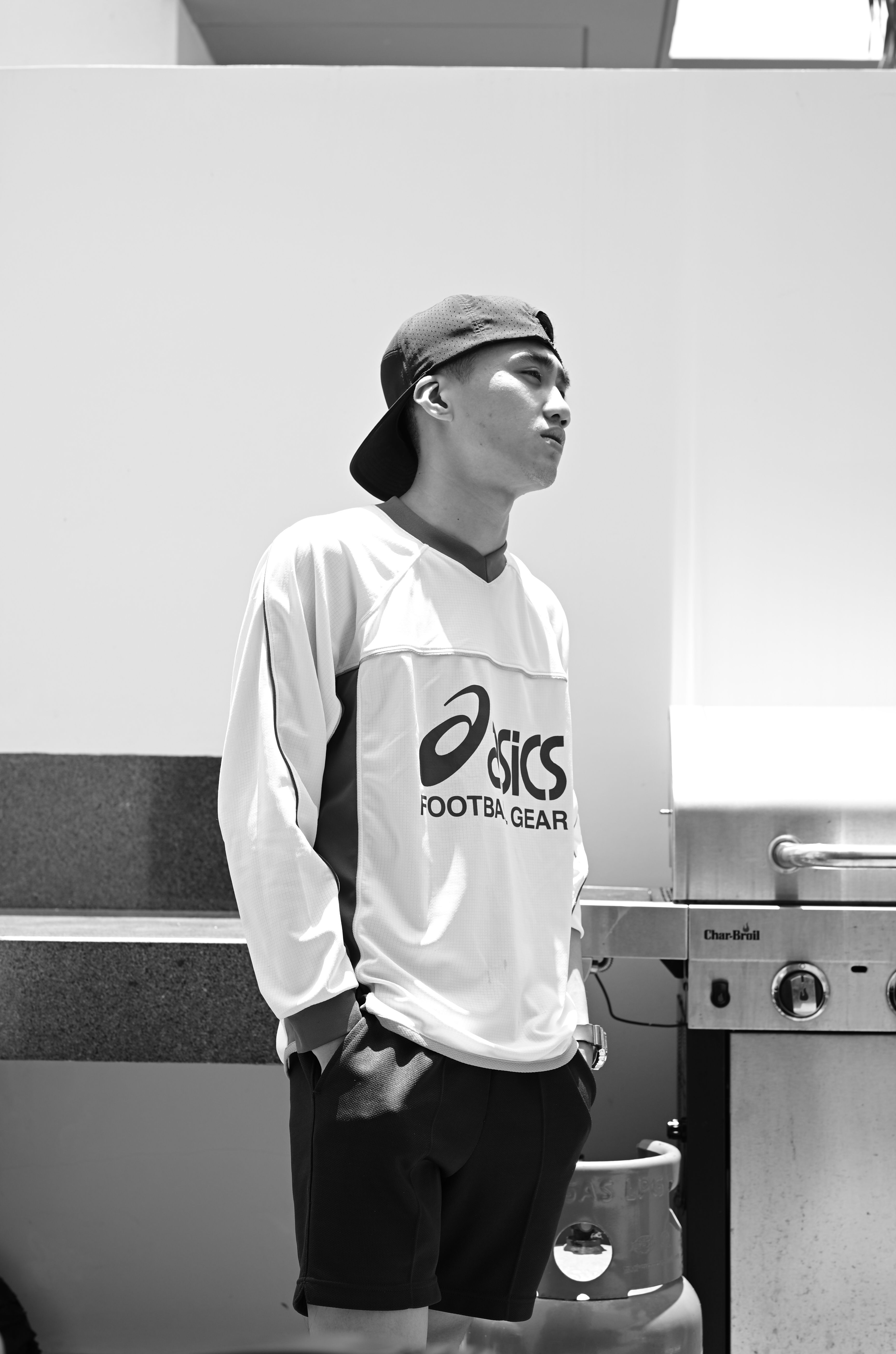 Stylish young man in casual sportswear standing by a barbecue grill, exuding a laid-back vibe.