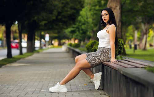 Free Fashionable woman in casual outfit sitting on a bench in Batumi, Georgia park. Stock Photo