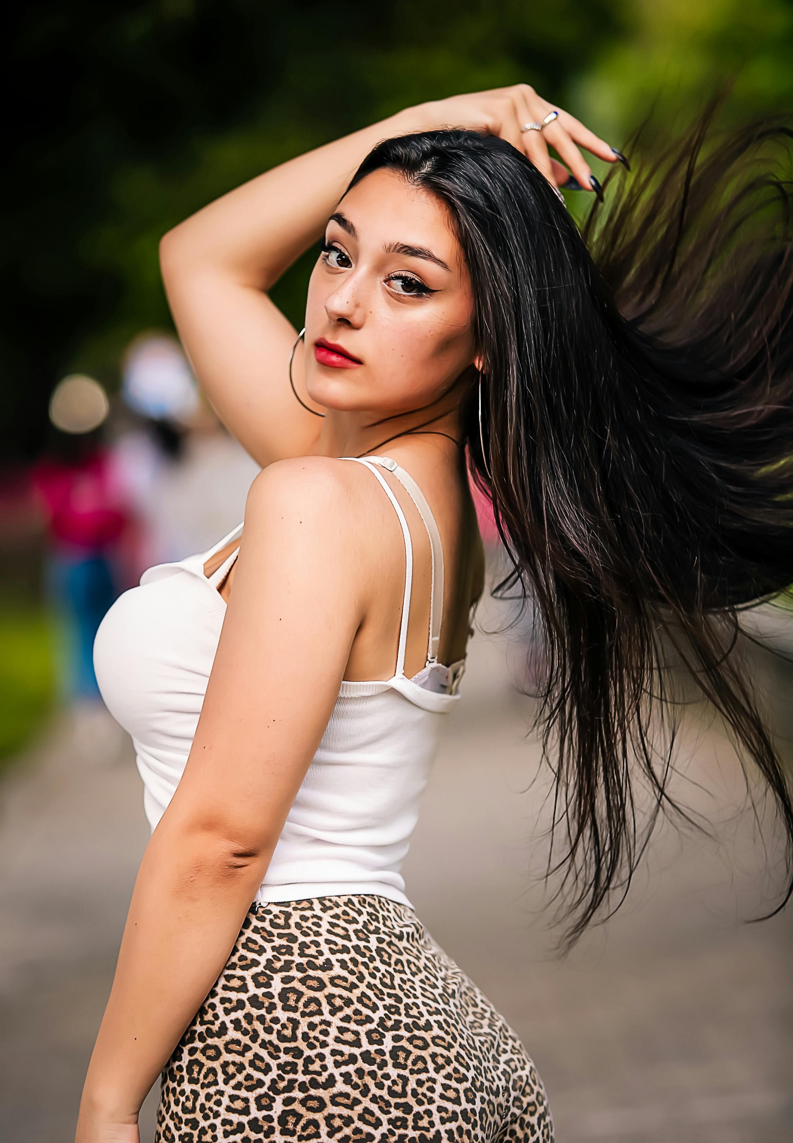 Elegant portrait of a woman with flowing hair in an outdoor setting, showcasing fashion style.