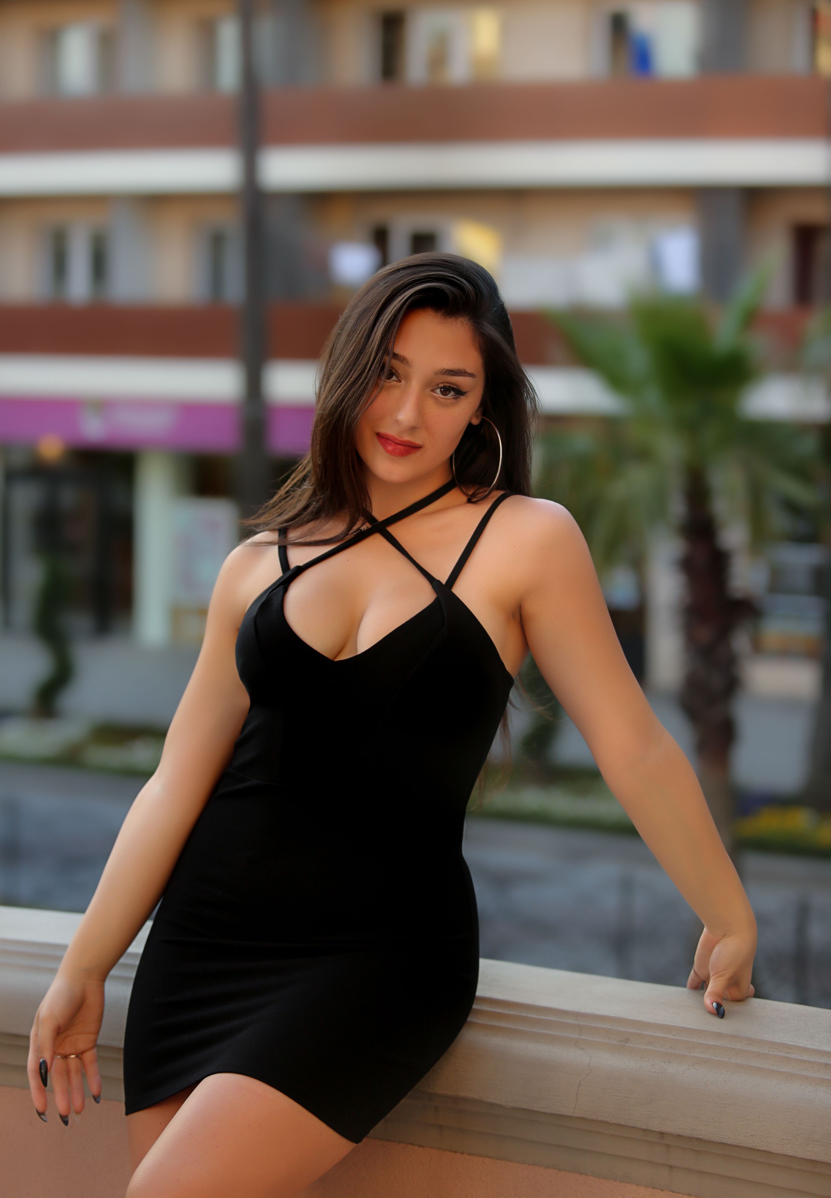 Stunning outdoor portrait of a woman in a black dress with natural expression and elegant pose.