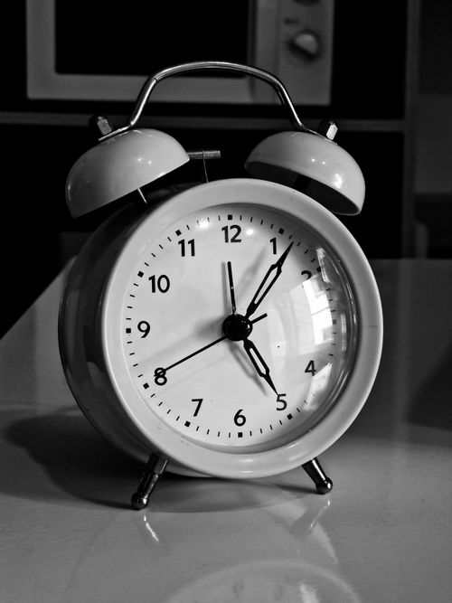 Free A monochrome photo of a vintage alarm clock displaying 7:10 AM, capturing a classic style and nostalgia. Stock Photo
