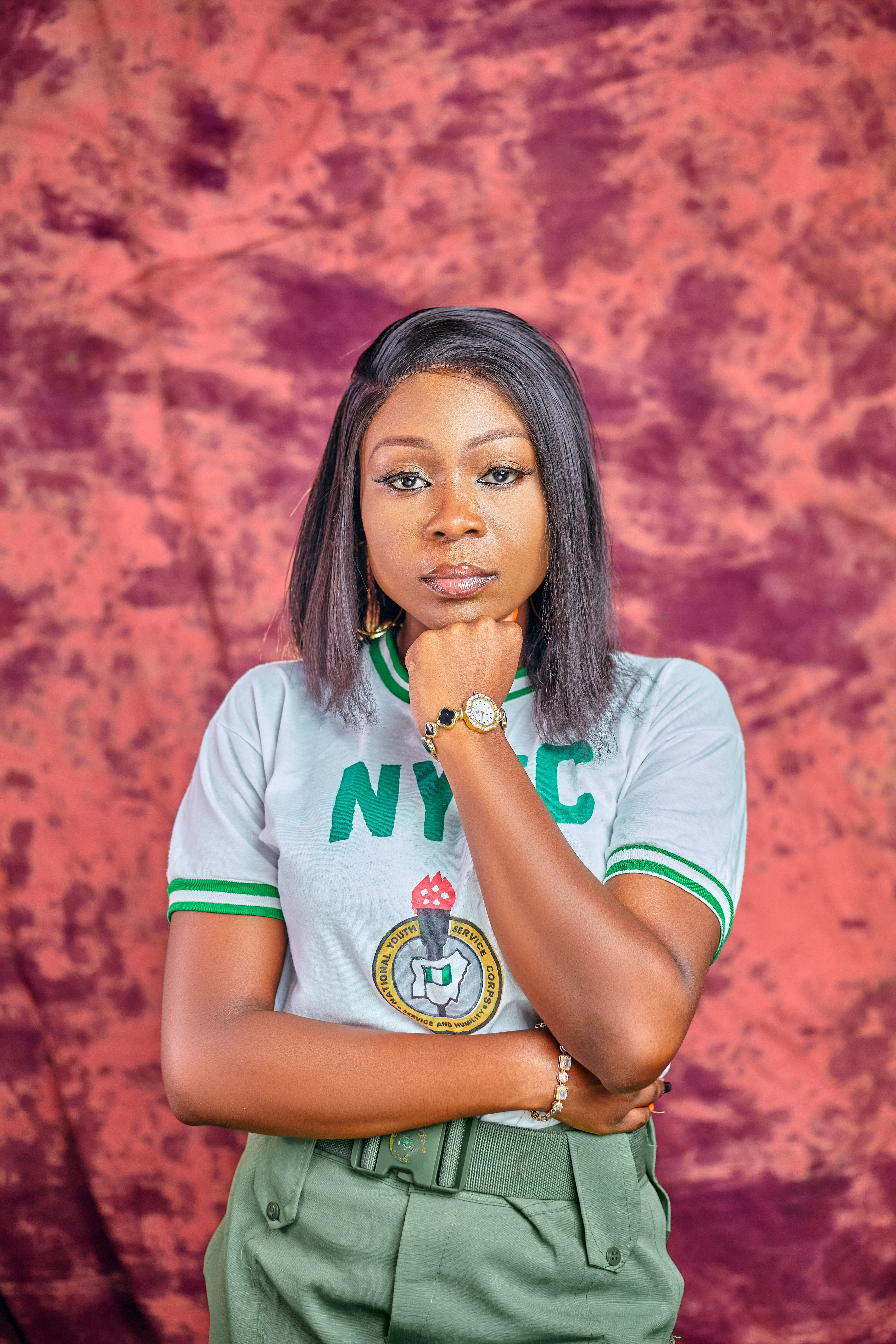 Portrait of a confident woman wearing the NYSC uniform against a vibrant backdrop.
