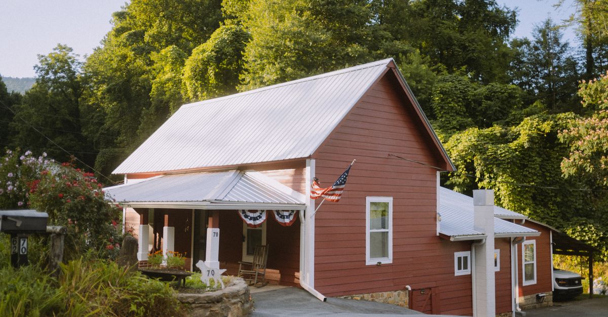 A picturesque red house nestled in the lush countryside of Clayton, Georgia, showcasing American rural charm.