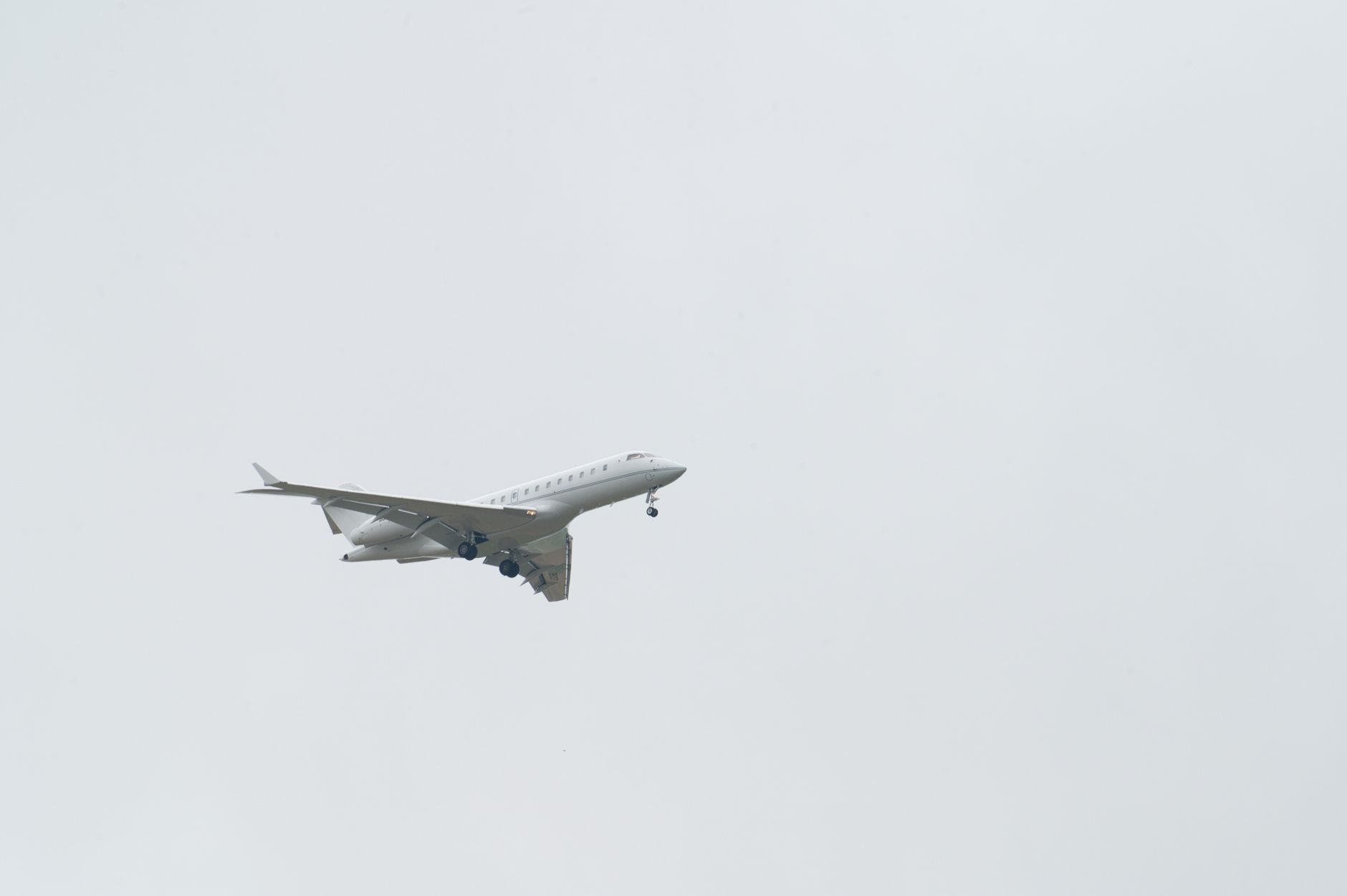 A silver private jet flying above clouds, representing the synchronous perimeter of global mobility networks.