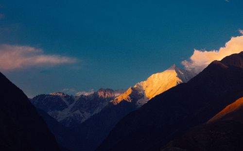 Free Golden hour view of snow-capped mountain peaks illuminated by sunset light against a vibrant blue sky. Stock Photo