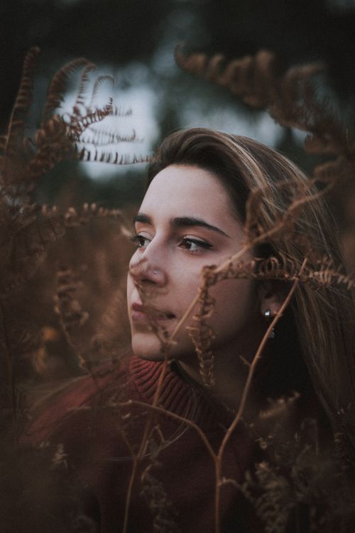 Free Close-up portrait of a woman surrounded by ferns, showcasing natural beauty. Stock Photo