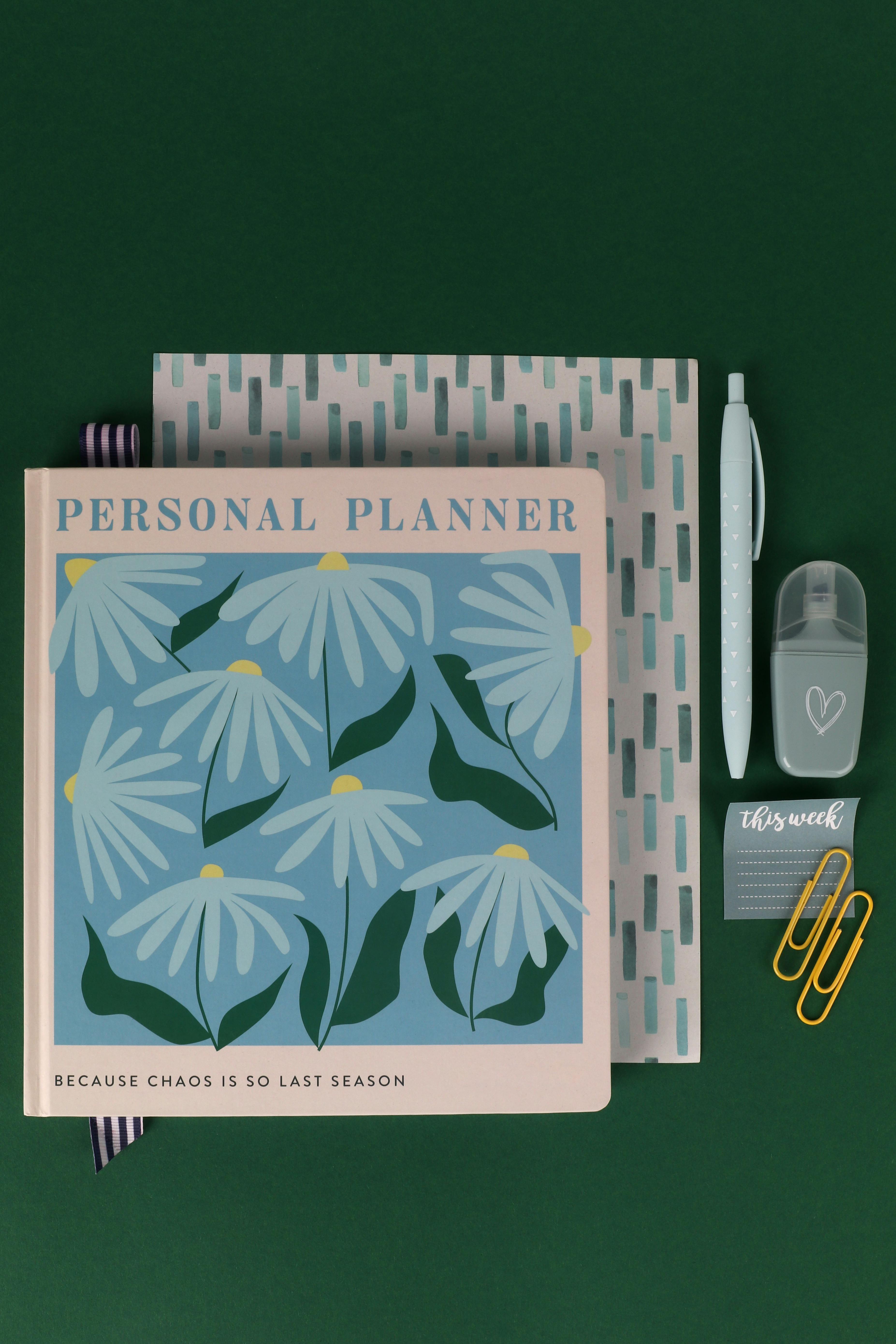 Stylish personal planner with floral design alongside stationery items, perfect for organization.