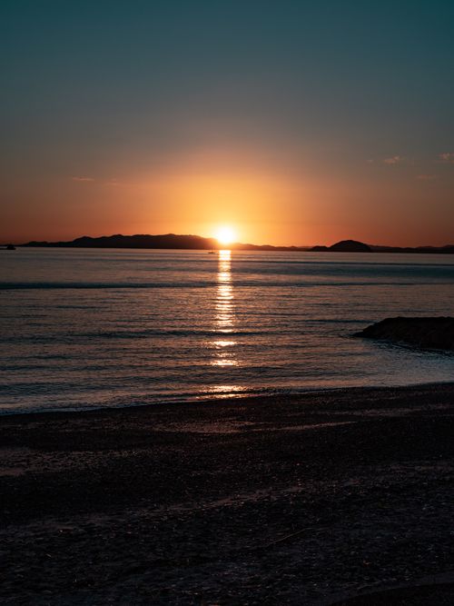 Free A breathtaking sunset with vibrant colors reflecting on the calm ocean waters. Stock Photo