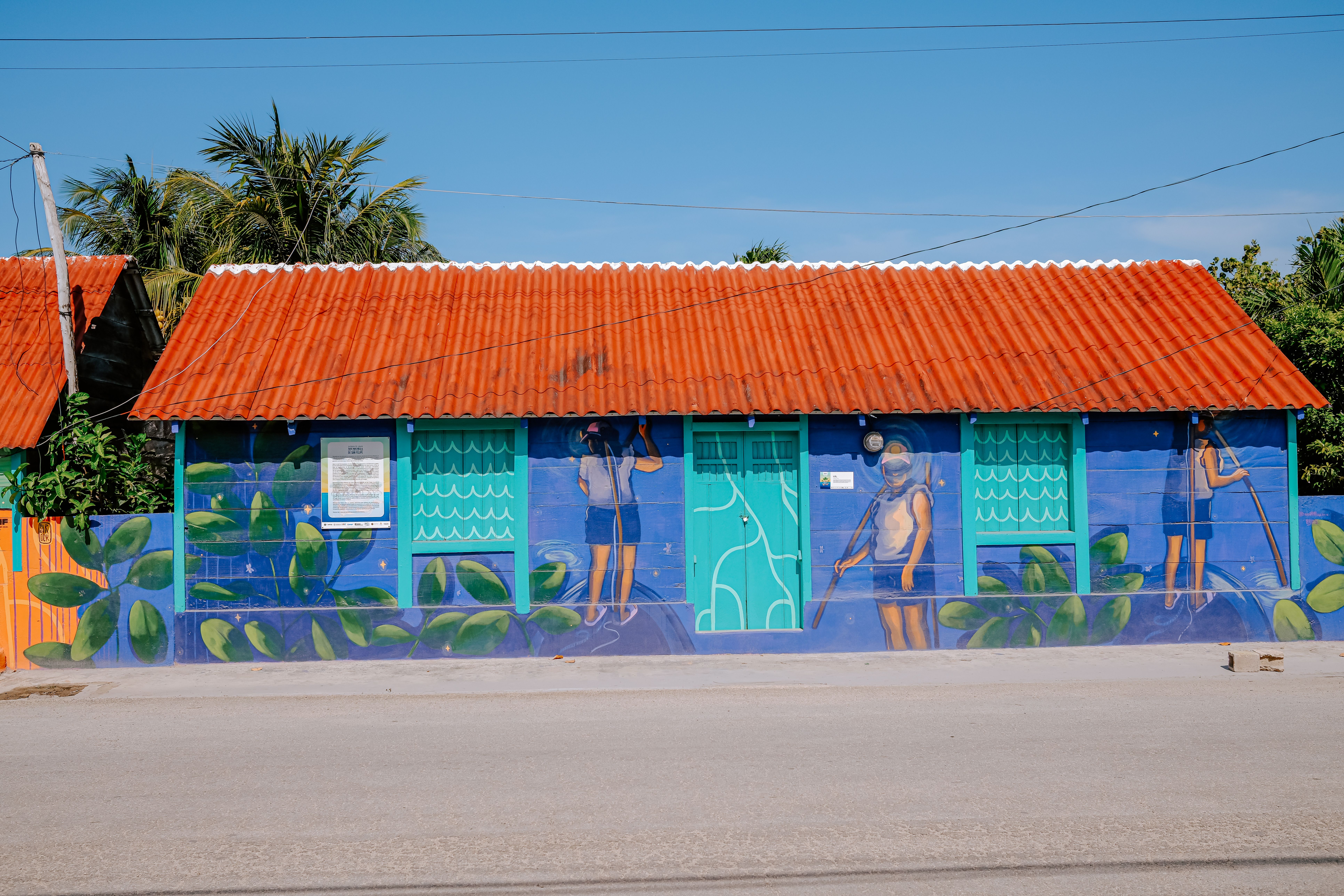 Brightly painted house with mural and red roof under clear sky.
