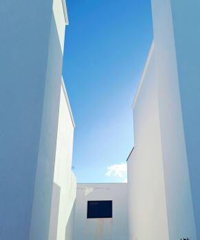 Minimalist white buildings with clear blue sky background, featuring modern architectural design.