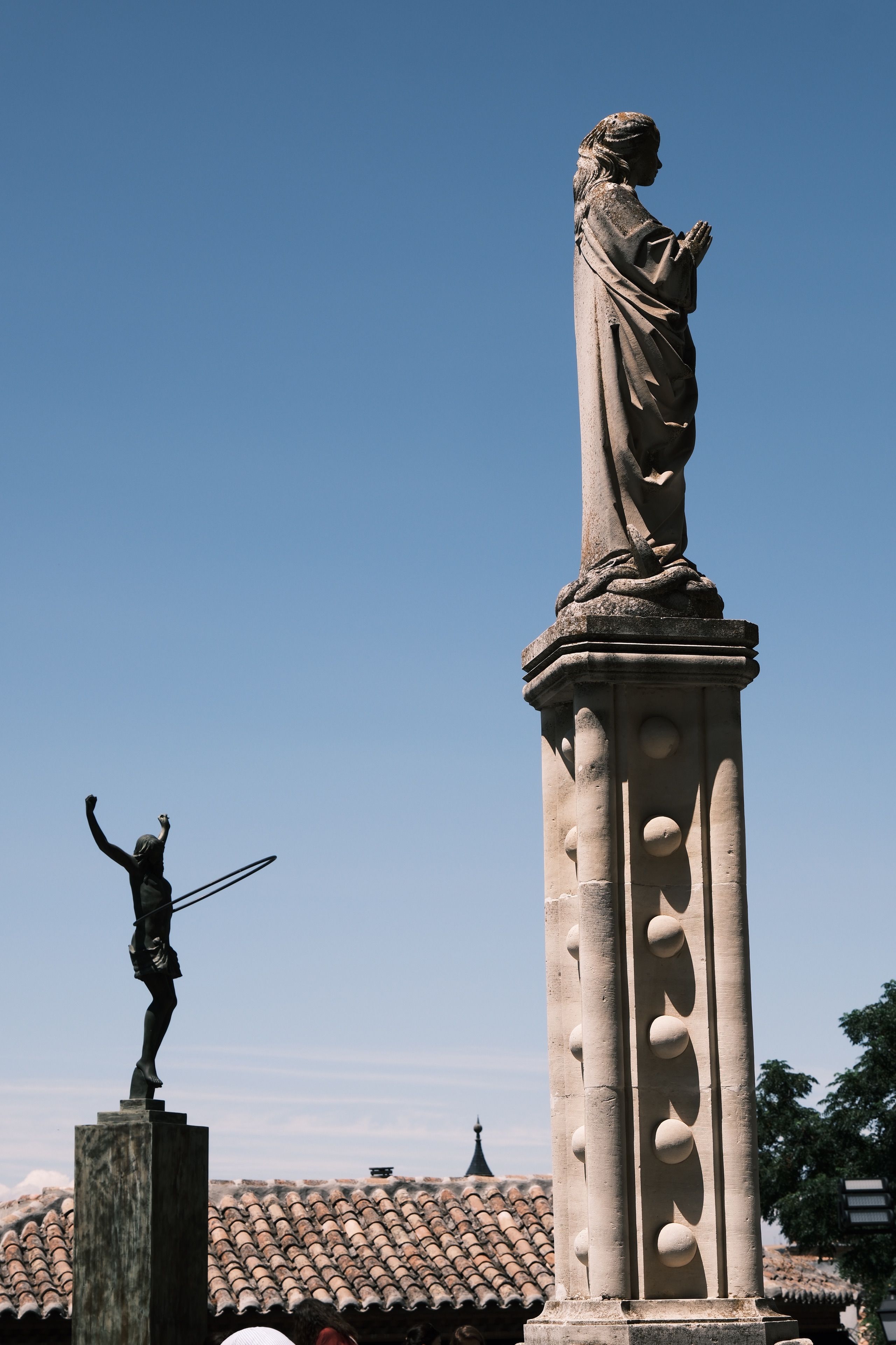 Two historic statues standing in a courtyard against blue sky