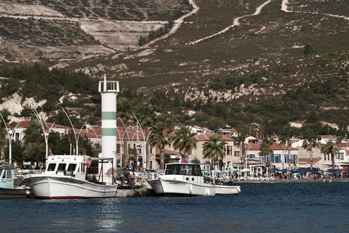 Free View of colorful fishing boats docked at Foça harbor with a scenic backdrop. Stock Photo