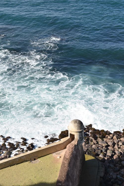 Free Ocean waves crash against a rocky shore with a coastal lookout. Stock Photo