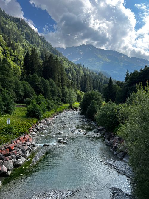 Free A picturesque alpine river flowing through lush Swiss mountains under a vibrant sky. Stock Photo