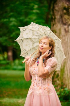 Woman in vintage dress with lace parasol in lush green park.
