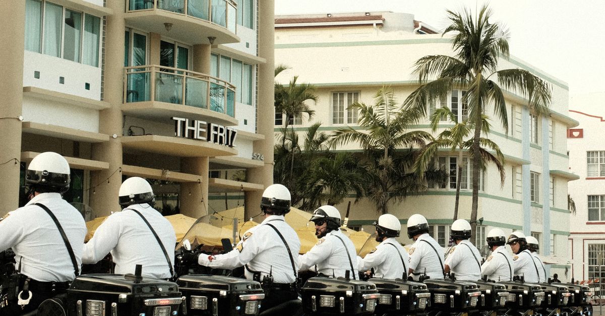 Line of motorcycle police officers in Miami Beach, capturing urban architecture and tropical vibe.