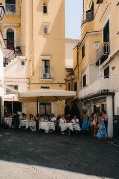 Outdoor dining scene in sunny Amalfi, Italy's picturesque coastal setting.