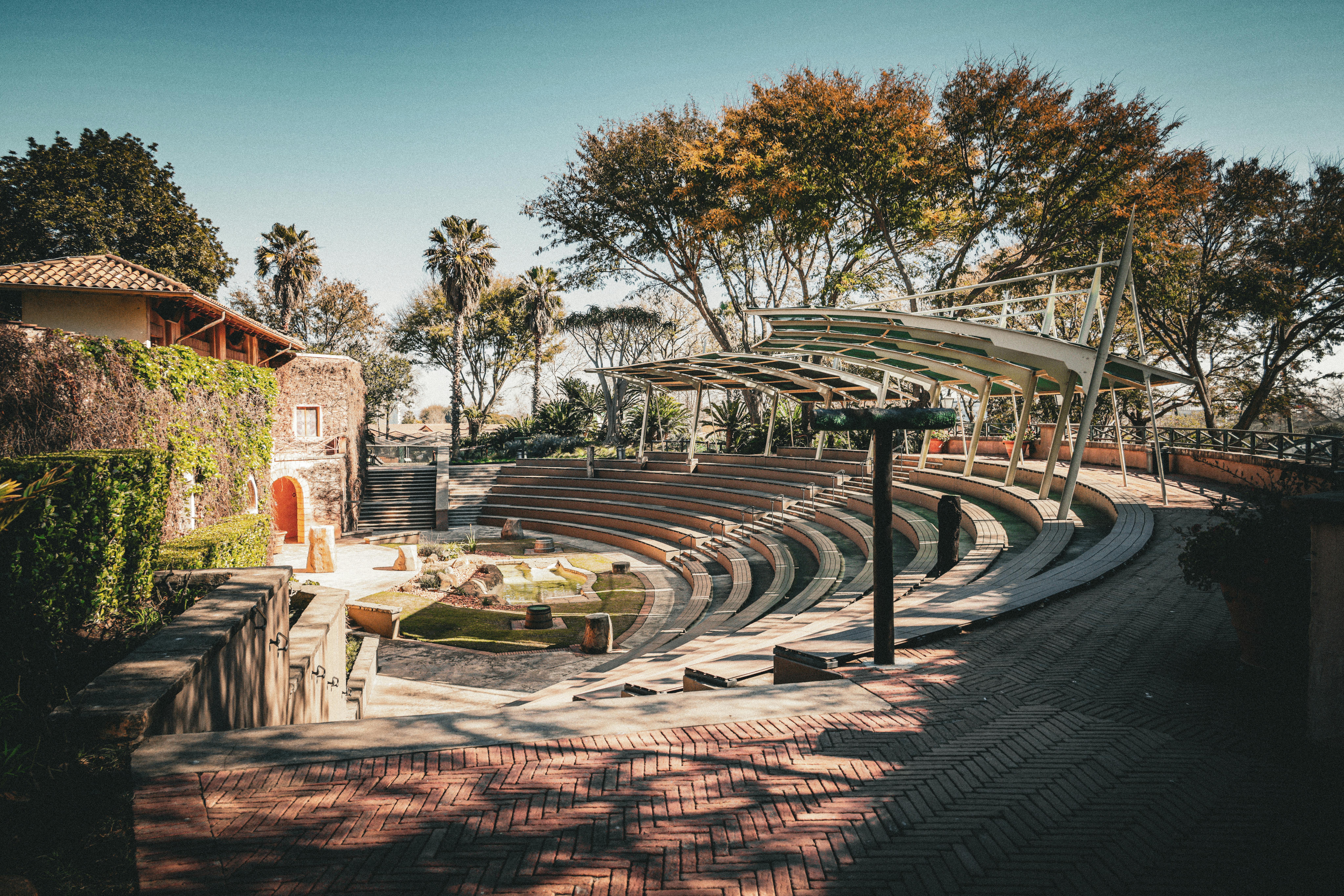 Bezpłatne Piękny amfiteatr na świeżym powietrzu z zaokrąglonymi siedziskami i zielonym tłem, idealny na imprezy. Zdjęcie z galerii