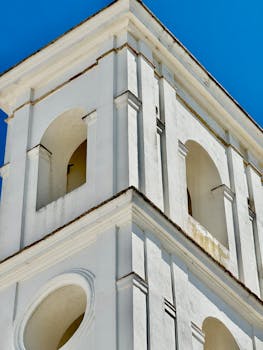 Detailed view of a white tower with arches in Cádiz, Spain under a vibrant blue sky.