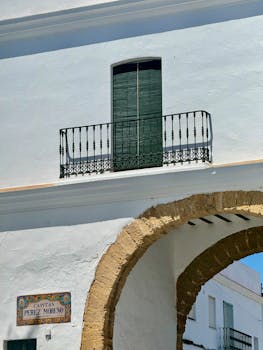 Sunlit white stucco building with an iron balcony in Cádiz, Andalucía, Spain.