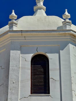 Close-up of white stucco church dome with architectural details in Cádiz, Andalucía.